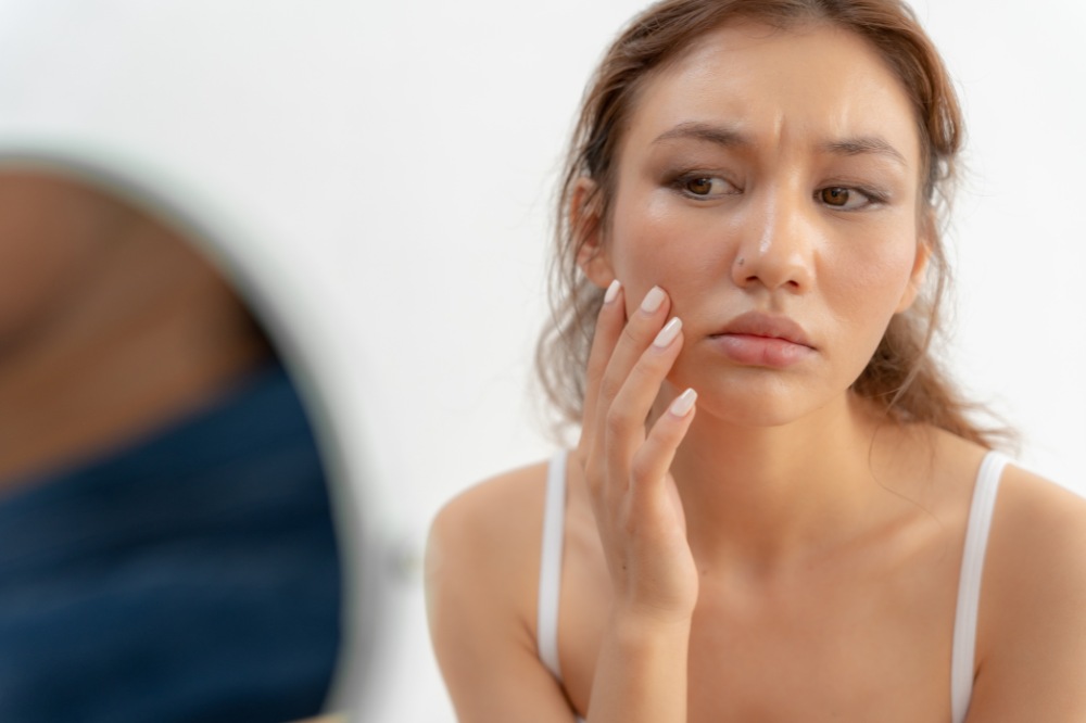 woman looking in mirror at facial skin